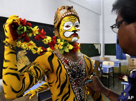 A dancer's body is painted to look like a yellow tiger before a performance.