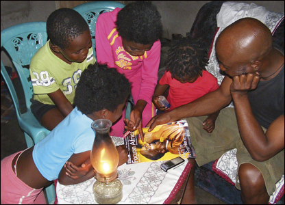 A family gathers round to look through the latest edition of BBC Focus on Africa 