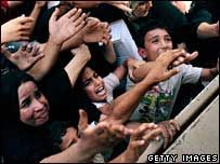 Bağdat'ta yiyecek ve battaniye dağıtan Amerikalı askerlerin dikkatini çekmeye çalışan halk