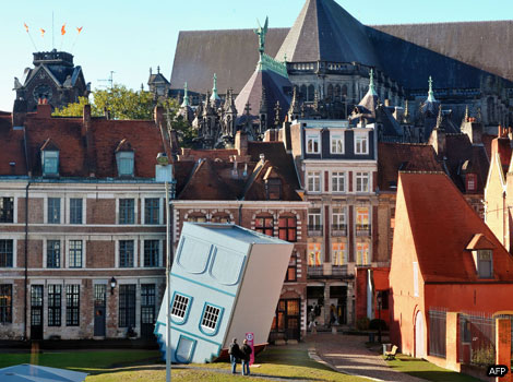 People watch an installation of an upside-down house in Lille.