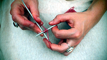 Hands holding knitting needles