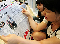 دو دختر کره ای در حال خواندن خبر آزادی گروگانهای هموطن شان در روزنامه