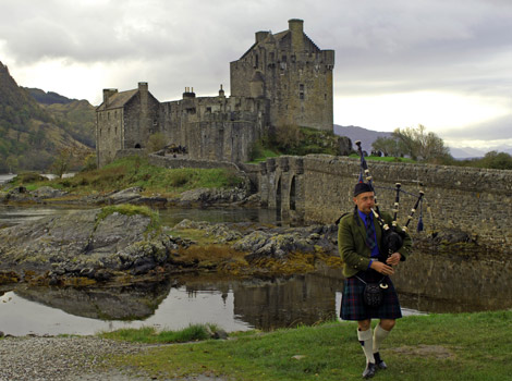A piper plays his bagpipes outside Eilean Donan Castle in Scotland