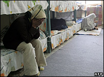 Một nữ tù nhân ngồi trên giường của mình, lấy tay che mặt