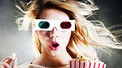 A girl wearing 3D glasses eating popcorn