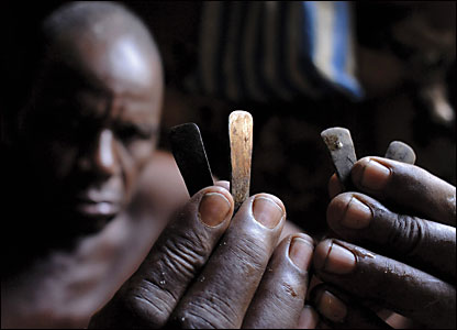 A man holds up the tools used for scarification.