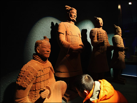 طفل صيني يتفقد احد جنود "جيش الطين"، وقد صنع من شوكولاتة