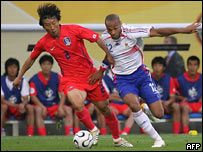 O coreano Kim (esq.) disputa bola com Thierry Henry durante a partida entre França e Coréia do Sul