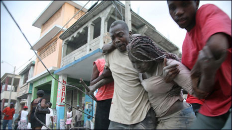 A Haitian woman is helped after being trapped in rubble in Port-au-Prince, Haiti