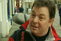 Cerwyn Jones yn ei gadair ar stryd yng Nghaernarfon