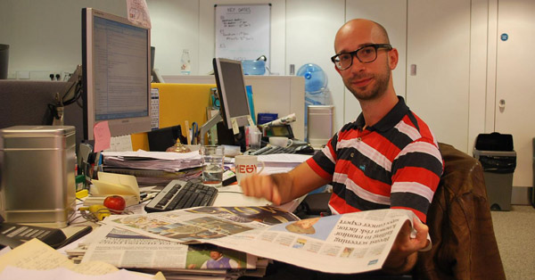 Sam sitting at a desk reading a paper