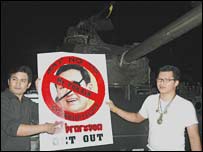 Hai người ủng hộ đảo chính đứng trước một xe tăng tại Bangkok