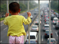 کودک چینی در حال تماشای صف خودروها در ترافیک خیابانهای پکن