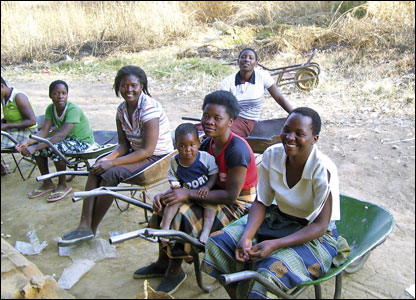 A group in a rural area take a rest on their wheelbarrows