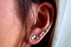 A woman's ear with many earrings