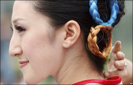 Một cô gái tình nguyện chỉnh dây buộc tóc hình biểu tượng Olympics trong lễ khai trương.