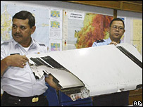 Hai viên chức cầm một mảnh của máy bay