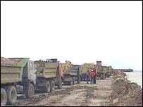 Російські самоскиди довозять ґрунт на будівництво дамби