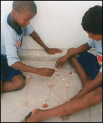 Meninas improvisam jogo usando pedras