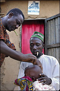 Two men administer scarring to a child