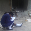 Zambian pupil takes notes by a family home