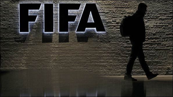 A man is silhouetted as he makes his way past the main entrance of FIFA headquarters