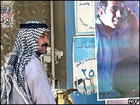 Arabský prodavač kávy v centru Bagdádu prochází kolem plakátu, který podporuje novou iráckou ústavu