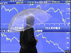 Một người đi ngang qua bảng chỉ số cổ phiếu ở Tokyo