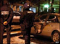 policiais olham carros queimados na frança