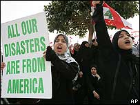 Manifestante pró-Síria exibe cartaz com dizeres: 'Todos Nossos Desastres vêm da América'