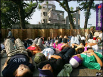 Populares se deitam em frente ao Domo da Bomba A durante a cerimônia em Hiroshima