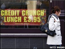 Một phụ nữ đi qua biển hiệu quảng cáo thời suy thoái ở Anh