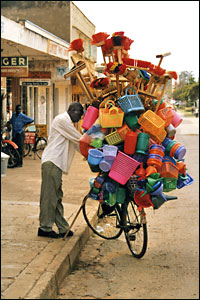 A bicycle tradesman loaded with brushes and baskets