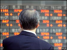 Một người xem bảng giá điện tử ở Tokyo