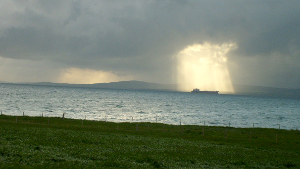 Freight ship sails through patch of sunlight