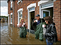 Some people drinking tea, standing in flood waters