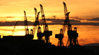 Cranes at a Clyde shipyard, silhouetted against a sunset.