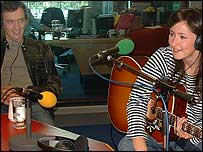 Luke watches as KT chats with Stewart.