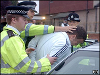 Polis gözaltına alınan bir kişiyi arabaya bindirirken