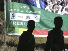  سربازان دولتی در برابر پوستر رابرت موگابه 