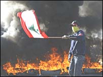 Manifestante com bandeira do Líbano, em meio à fumaça