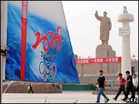 Uighar Muslims walking past Beijing Olympics sign in Kashgar