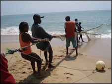Fishermen bring in a net on the beach