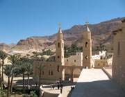 Sand-coloured buildings in the desert with Christian crosses atop two towers