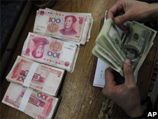 6 January 2010: A bank clerk counts dollars and yuan notes for a customer at a bank in Hefei, in central China's Anhui province