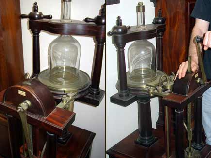 Hand-powered vacuum pump designed by Robert Boyle: a mahogany framework encloses a thick glass bell jar on a brass plate. Simple machinery attached lower down allows a handle to be turned to extract air from the jar