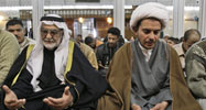 A Shiite, in white turban, prays next to a Sunni Sheik in Baghdad