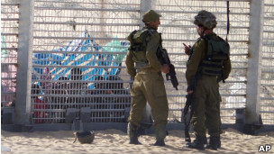 Soldados israelenses vigiam africanos que tentam entrar no país por cerca na fronteira com o Egito (Foto: AP)