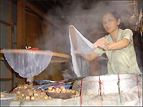 Một phụ nữ đang làm bánh cuốn