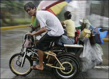 Một người đàn ông cùng gia đình đi trên đường phố Manila dù gió to